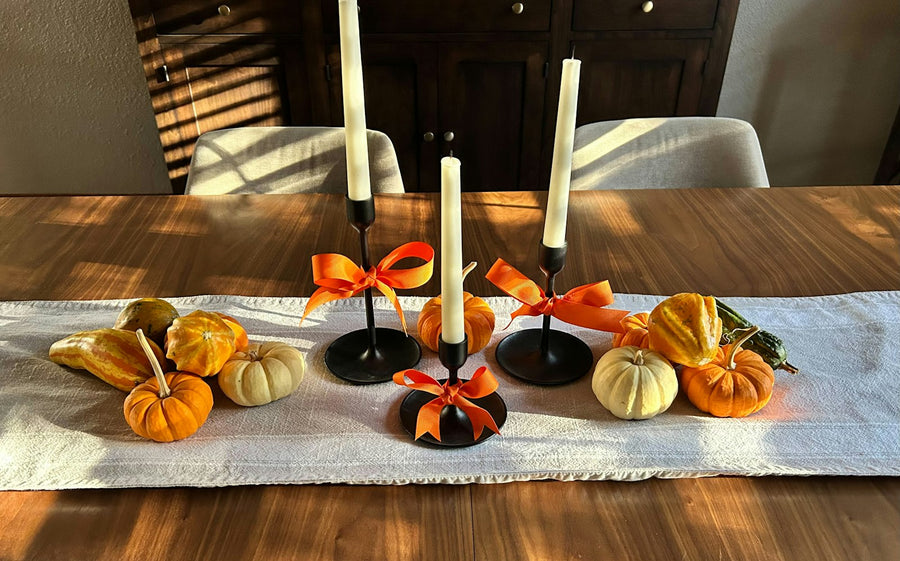 Candlesticks with small pumpkins and gourds on a table runner