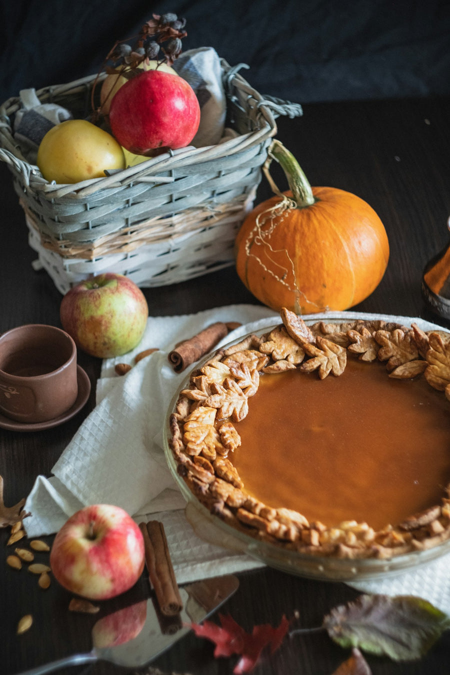 Pumpkin pie with a leaf crust beside a pumpkin